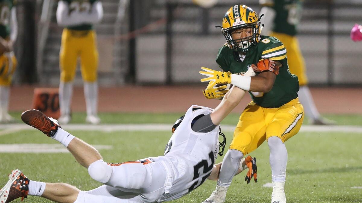 Edison High's Isaiah Palmer eludes a tackle by Jake Graham during a Sunset League game against Huntington Beach on Friday.