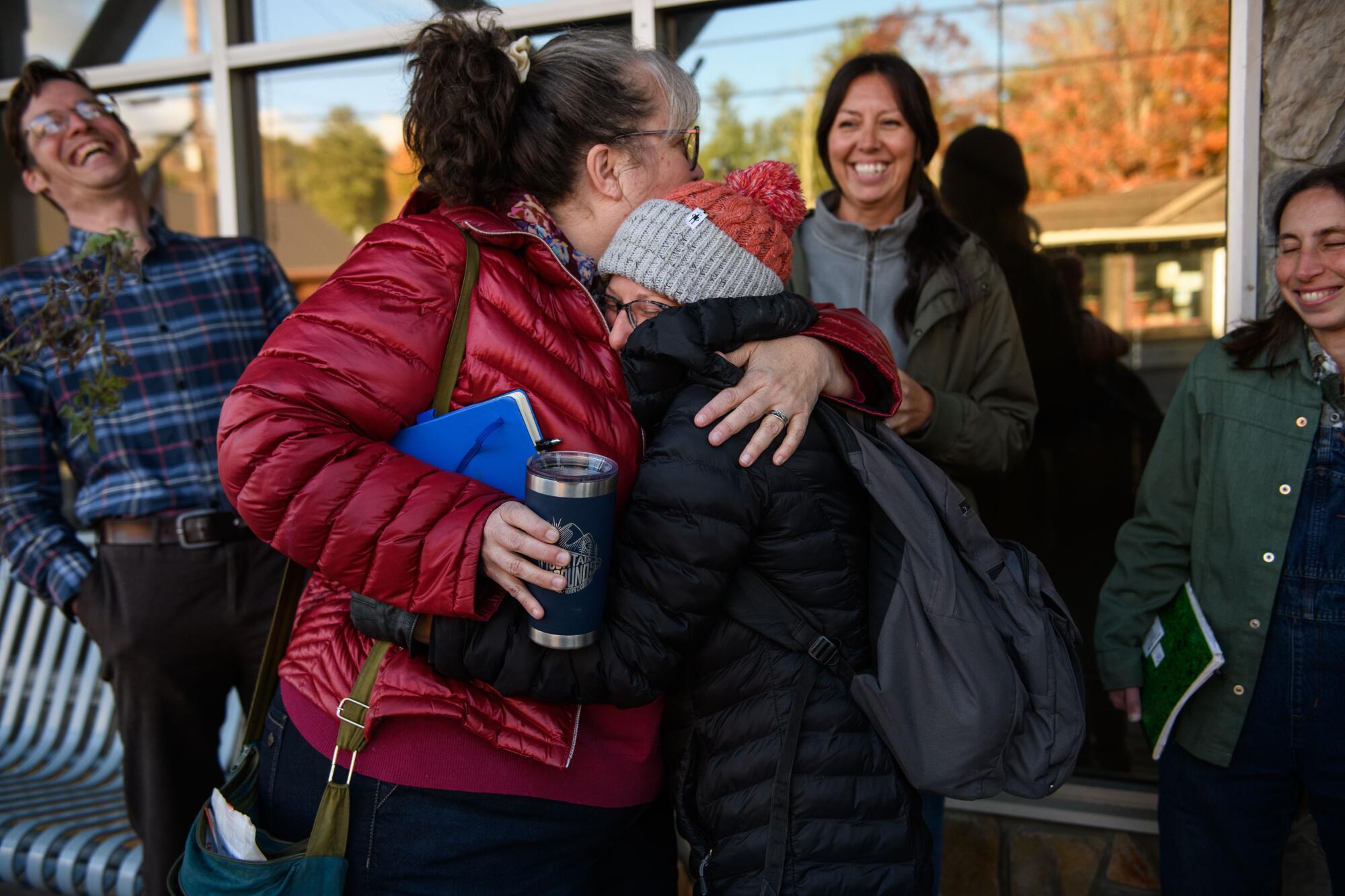 Suzanne Fischer, left, and Tiffany Weitzen greet each other with a hug before a meeting of the Avery County Democratic Party.