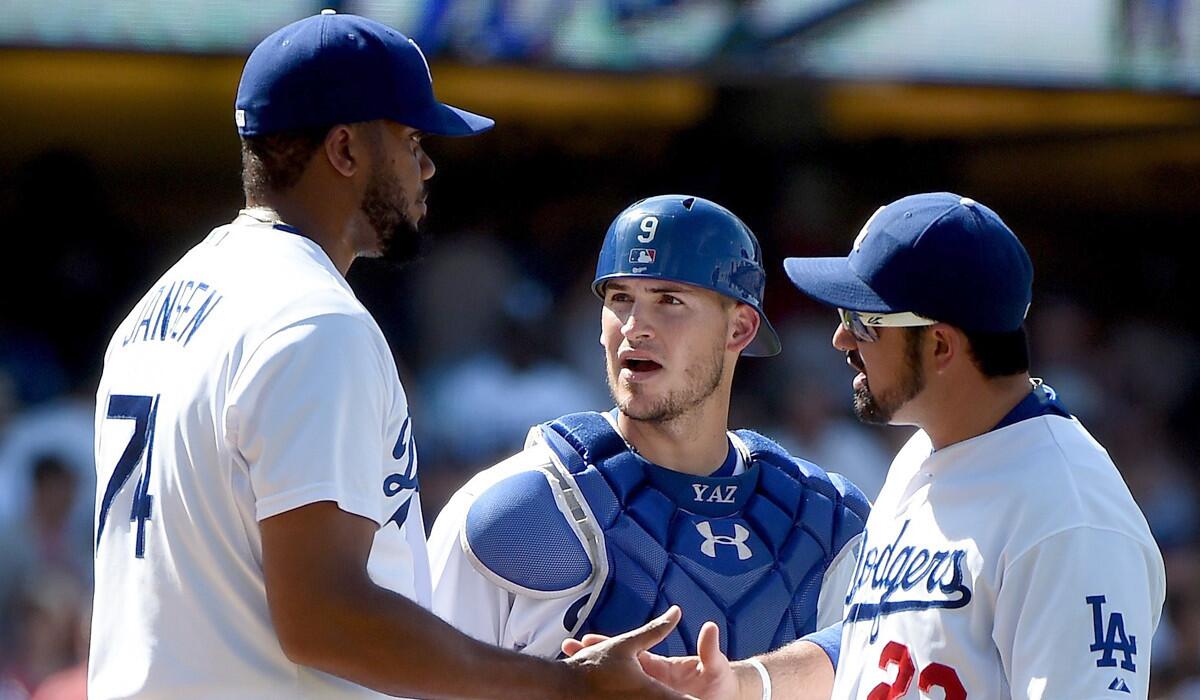 Kenley Jansen, left, celebrates the Dodgers' 3-1 win over the Angels on Saturday with teammates Yasmani Grandal and Adrian Gonzalez.