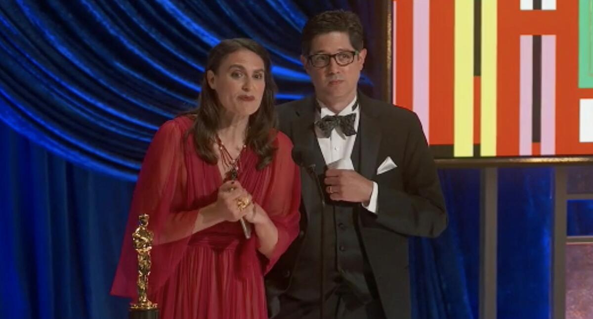 A woman and a man accepting an Oscar trophy