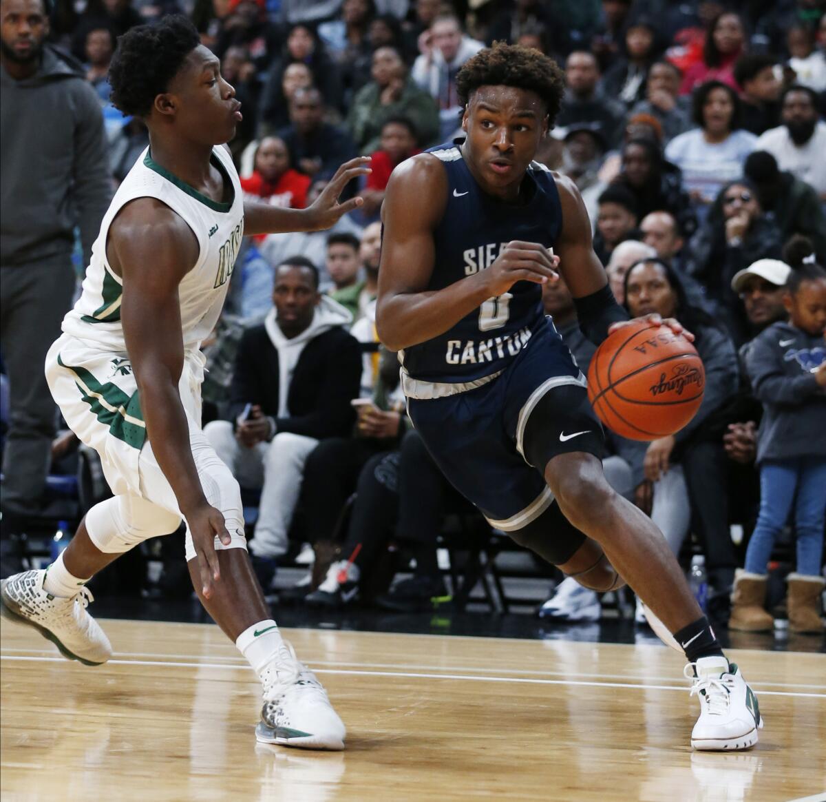 Sierra Canyon's Bronny James (0) drives against St. Vincent-St. Mary's Darrian Lewis during a game on Dec. 14, 2019, in Columbus, Ohio. James won't be under his father's watchful eye on Friday when playing against Mater Dei.