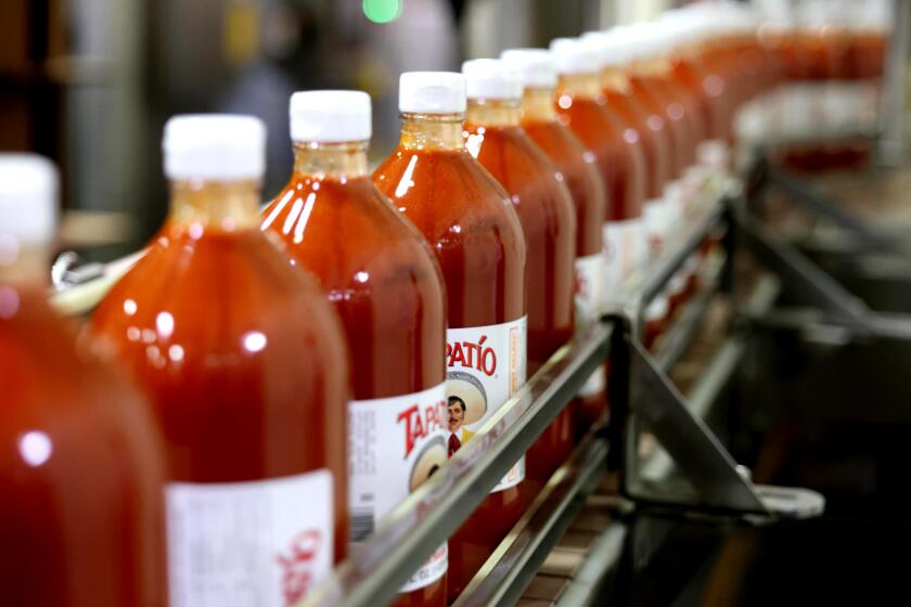 VERNON, CA - April 08, 2026: After bottles of Tapatio hot sauce are filled and labeled, they continue down a conveyer to be boxed at the Tapatio manufacturing facility on Wednesday, April 8, 2026 in Vernon, CA. The hot sauce company was recently acquired by Dallas-based private investment firm, Highlander Partners. The acquisition was part of broad efforts to help the company find national success. The company was founded in 1971 by Jose-Luis Saavedra, a Mexican immigrant who launched the brand out of his family's Maywood home. The company was completely family-owned before this acquisition. (Genaro Molina/Los Angeles Times)