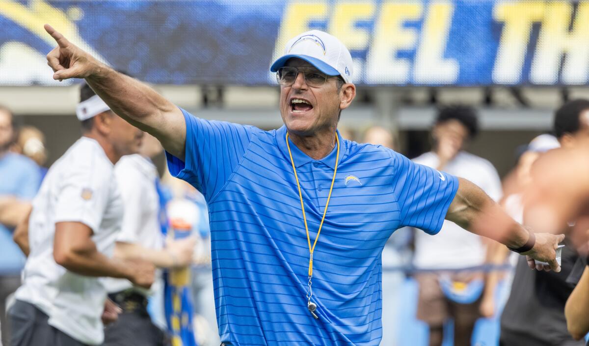 Coach Jim Harbaugh signals his Chargers from the sideline.