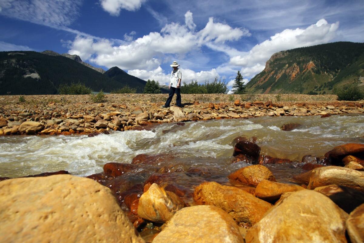 Melanie Bergolc walks along the banks of Cement Creek in Silverton, Colo., on Aug. 10. The area is a few miles downstream from the Gold King Mine.