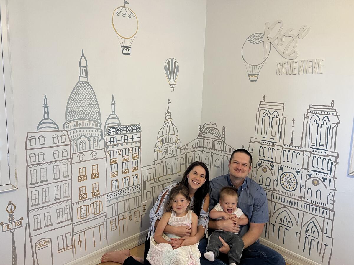 The Lehman family — Diane and Billy with children Rosie and William — sit in front of a Paris cityscape that Diane painted.