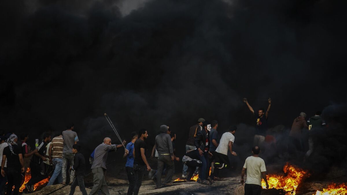 Protesters make their way into the black smoke during a border protest in Buriej, near Deir al-Bala, Gaza, on May 15.