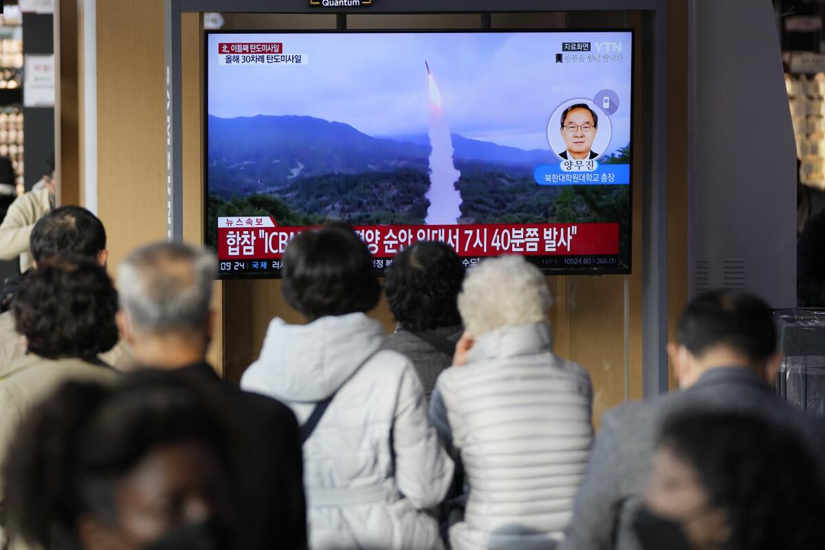 People watch a TV screen showing a news report about North Korea's latest missile launch.