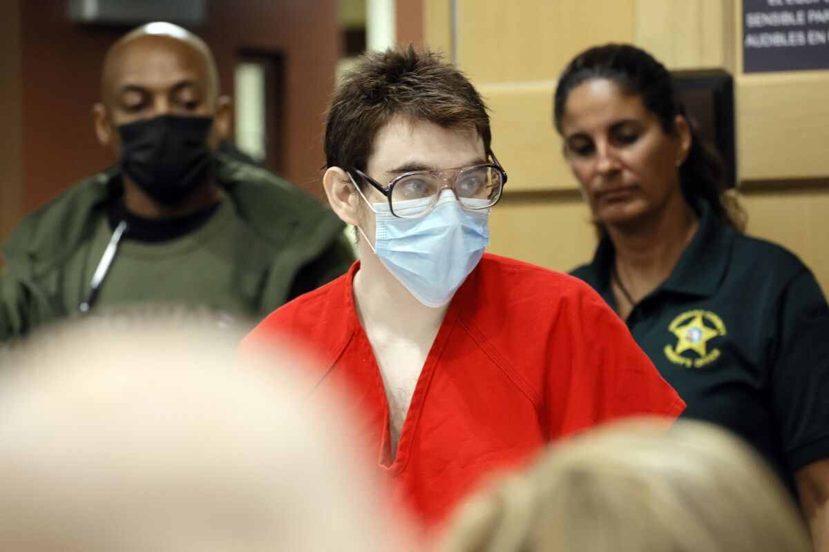 Nikolas Cruz wears a face mask and enters a courtroom for a hearing.