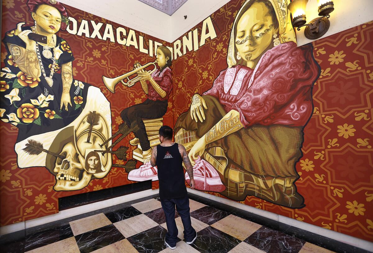 Dario Canul of Tlacolulokos examines a portion the collective's new mural at the L.A. Public Library.