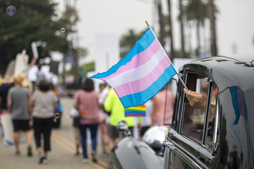 Long Beach, CA - July 10: A person holds a flag out of a vehicle window during the 39th annual Long Beach Pride Parade on Ocean Boulevard Sunday, July 10, 2022, in Long Beach, CA. The Long Beach Pride Parade is back after being on hiatus due to the pandemic. (Francine Orr / Los Angeles Times)