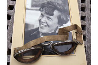 An unpublished personal photo of Amelia Earhart dated 1937, along with goggles she was wearing during her first plane crash