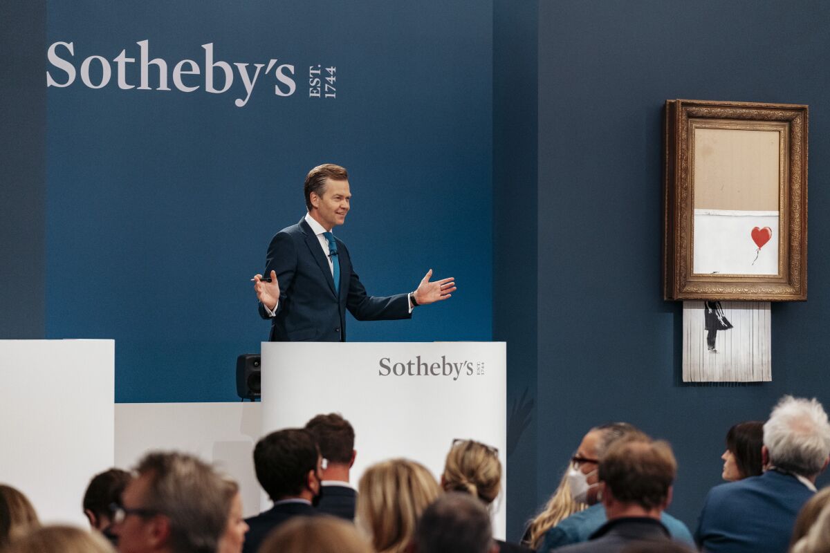 In this handout photo provided by Sotheby's Auction House, the auction for Banksy's "Love is the Bin" takes place in London, Thursday, Oct. 14, 2021. A work by British street artist Banksy that sensationally self-shredded just after it sold for $1.4 million has sold again for $25.4 million at an auction on Thursday. “Love is in the Bin” was offered by Sotheby’s in London, with a presale estimate of $5.5 million to $8.2 million. (Haydon Perrior/Sotheby's Auction House via AP)
