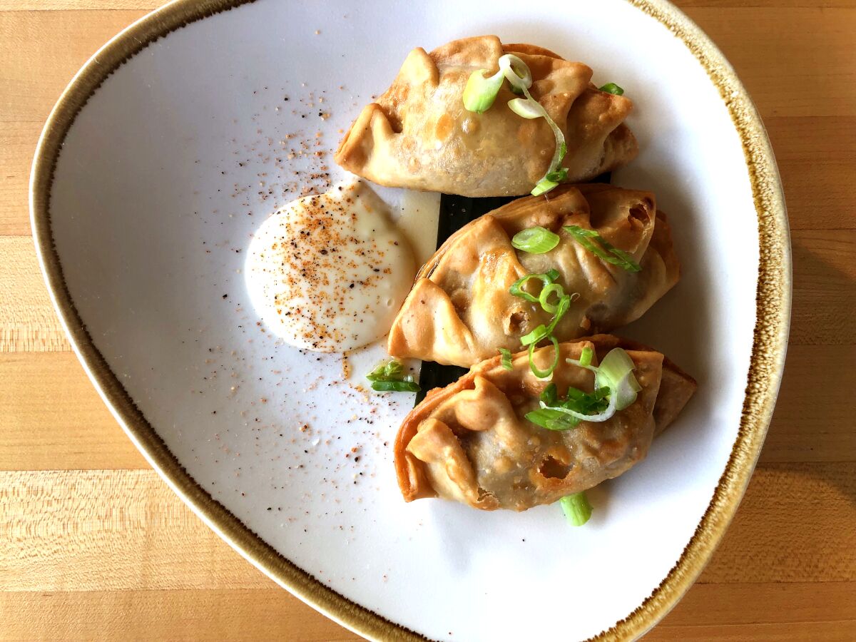 Adobo empanada comes to the table flaky and three to a plate.