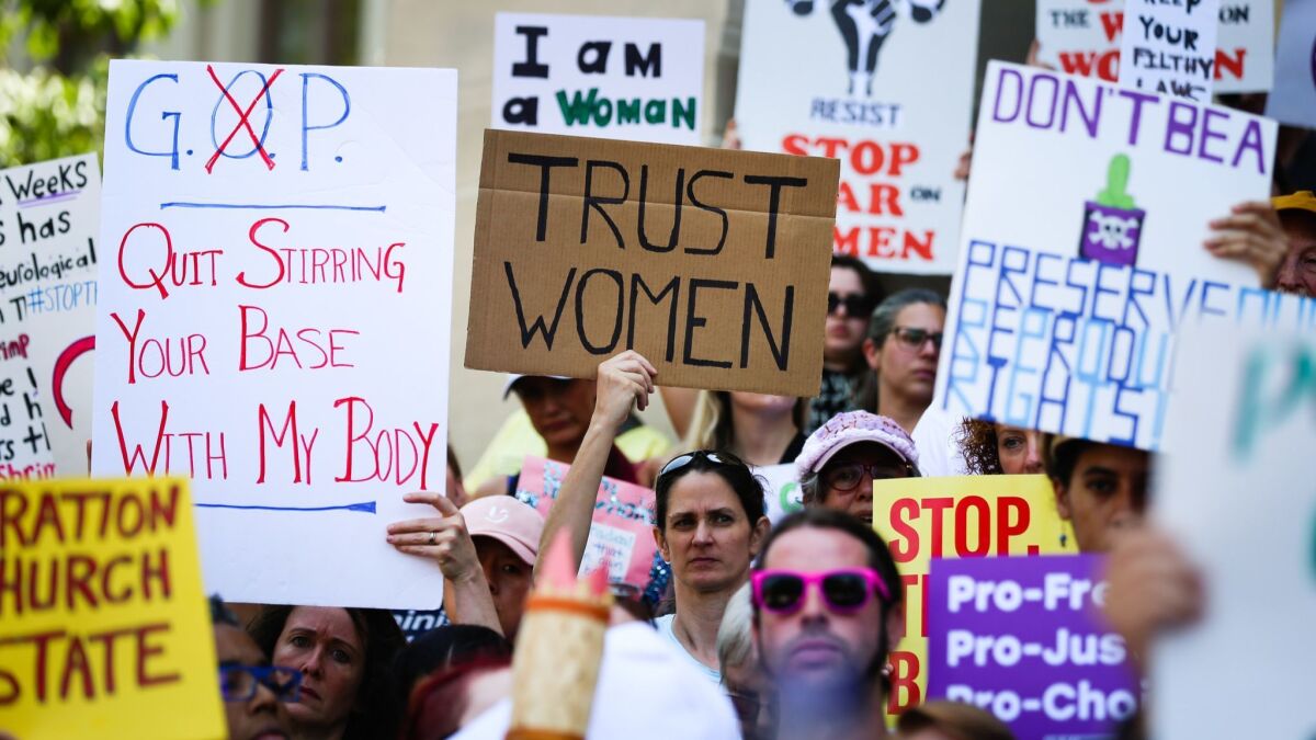 Women hold signs during a protest against recently passed abortion ban bills at the Georgia State Capitol building, on May 21, 2019 in Atlanta.