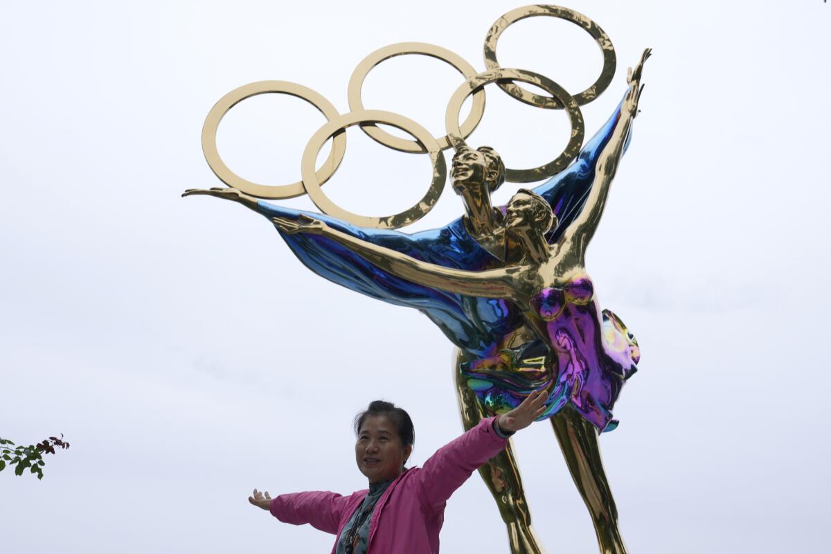 Un turista en el parque Shougang posa para fotos frente a una escultura de los anillos de los Juegos Olímpicos 