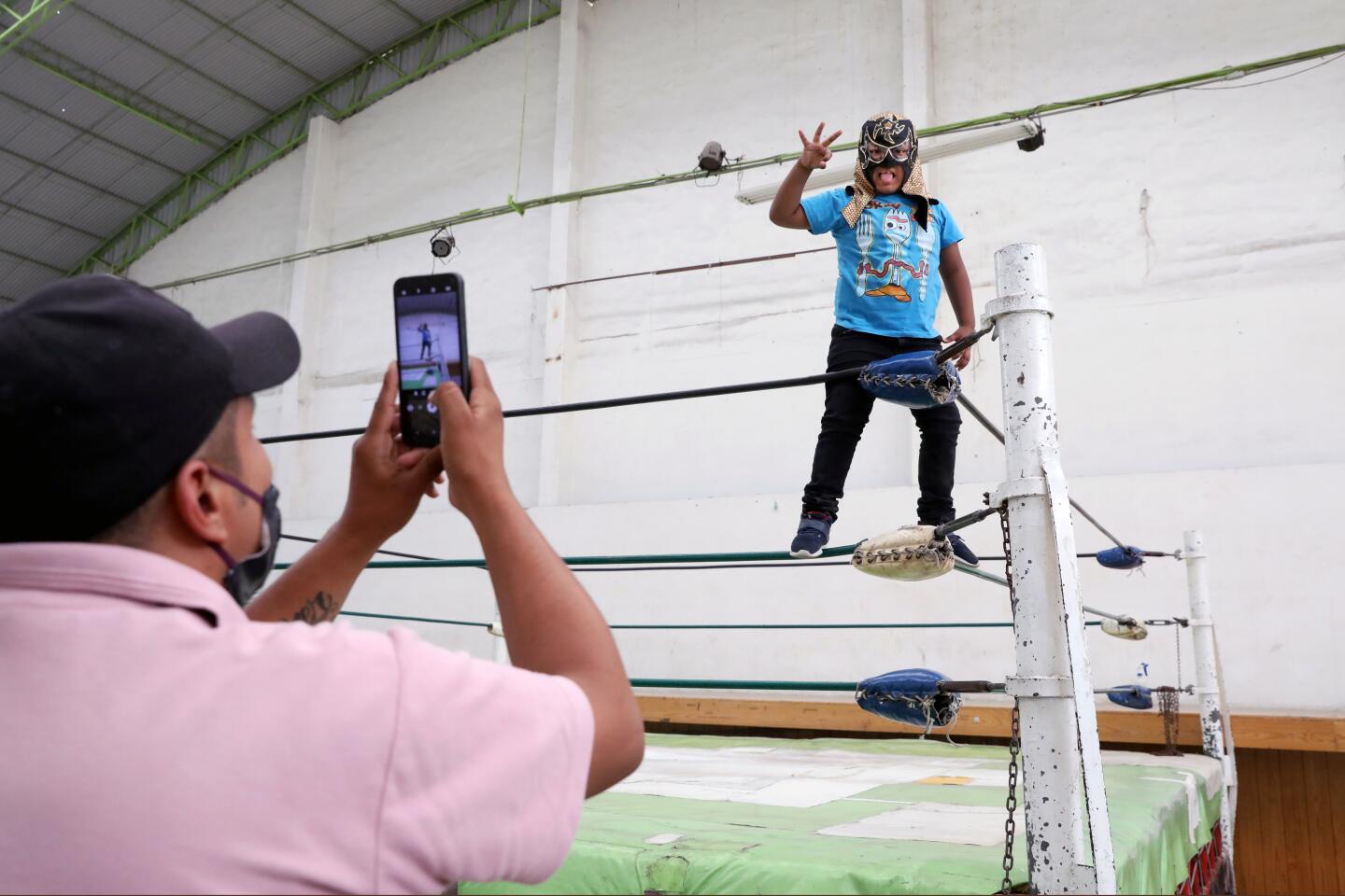 Alonso Hernandez takes a photo of his 7-year-old son, Cristopher, after a lucha libre event in Ecatepec, Mexico.