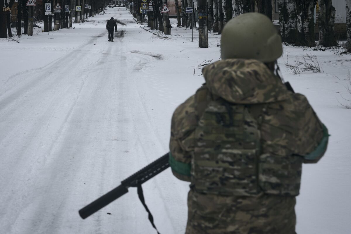 Ukrainian soldier patrolling a snow-covered street in Bakhmut