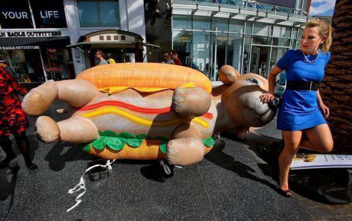 Jeni Haines, national campaign coordinator for Mercy for Animals, walks past a 10-foot inflatable puppy in a bun at the intersection of Hollywood Boulevard and Highland Avenue on Monday.