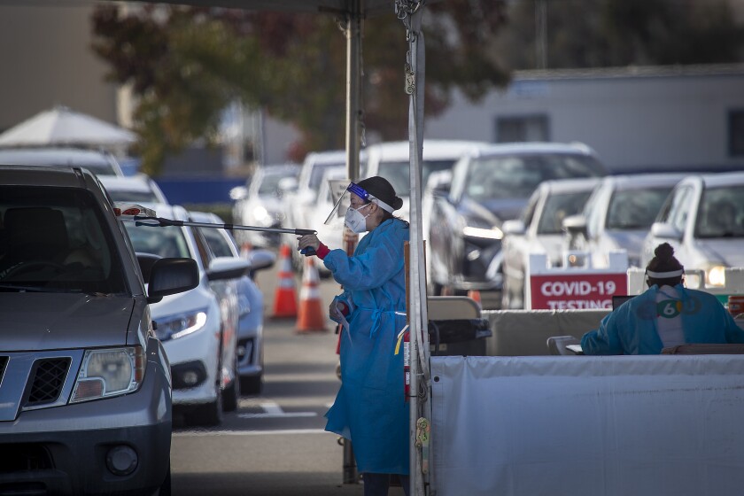 COSTA MESA, CA - NOVEMBER 12: 360 Clinic health care workers working with the Orange County Health Care Agency and city of Costa Mesa conducts testing at the drive-through self-administered COVID-19 testing super site at the Orange County Fair & Events Center on Thursday, Nov. 12, 2020 in Costa Mesa, CA. California is approaching 1 million cases, although the spread remains slower in the state than in other hot spots across the country. (Allen J. Schaben / Los Angeles Times)