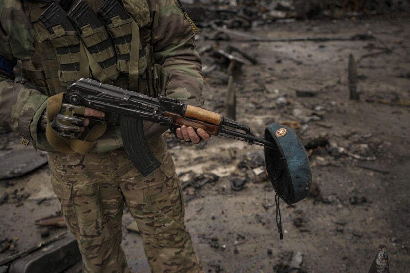 A Ukrainian serviceman with a Russian beret of destroyed Russian military vehicles on his weapon, at Antonov airport 