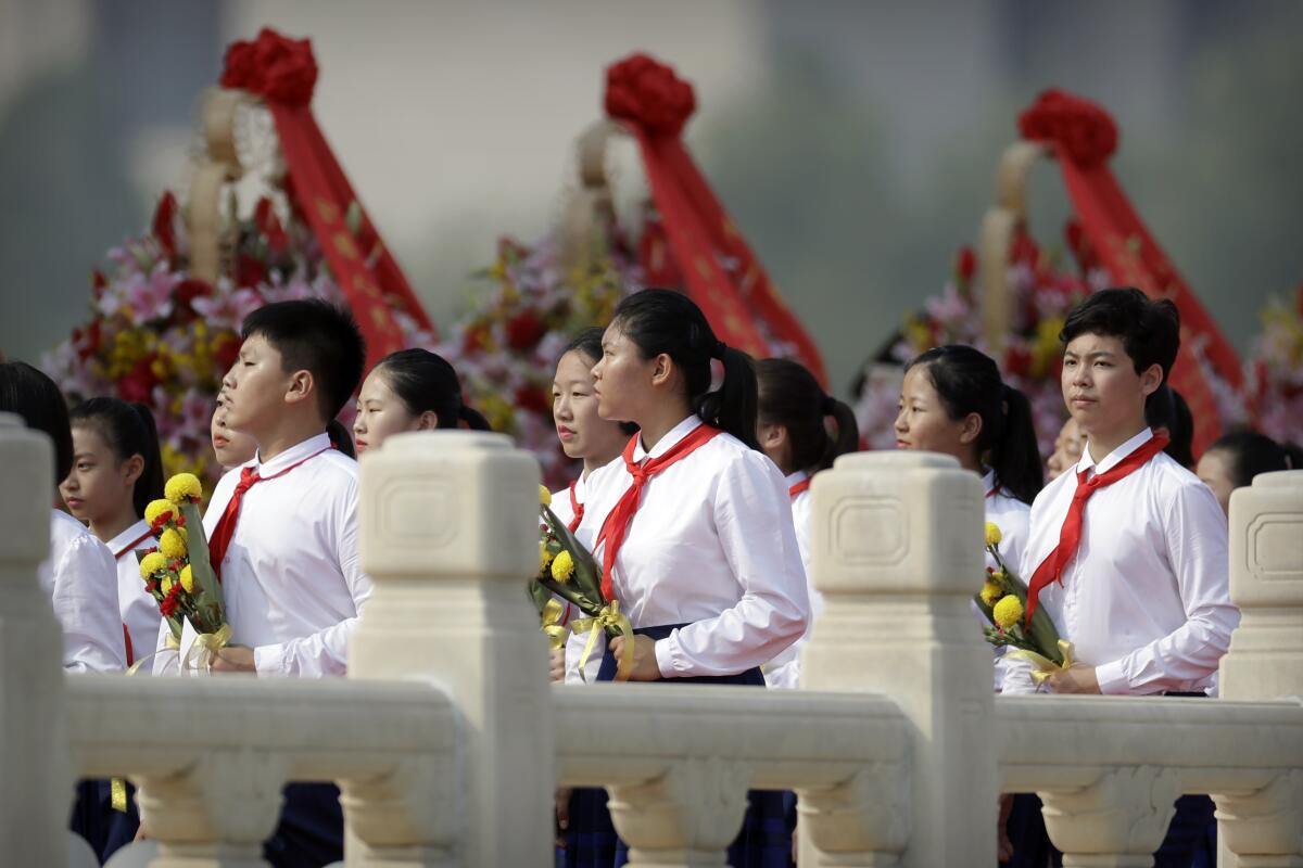 Chinese schoolchildren carry flowers as they walk past wreaths at the Monument to the People's Heroes in Beijing.