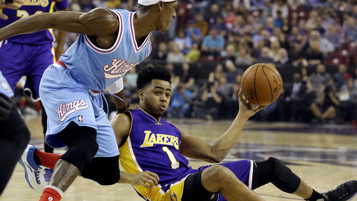 Lakers guard D'Angelo Russell, right, tries to pass after falling as Sacramento Kings guard Rajon Rondo tries to block the pass.