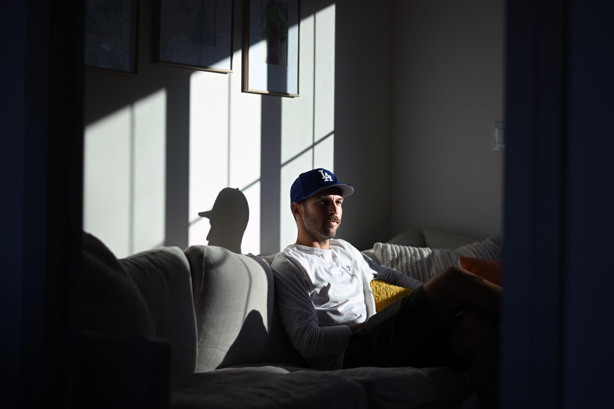 LAFC defender Ryan Hollingshead sits on a couch in his home as sunlight hits his face