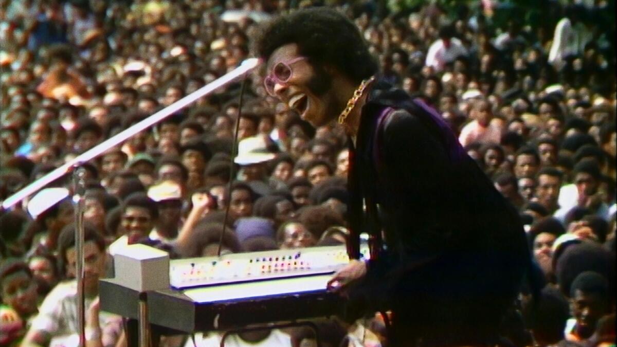 A man playing a keyboard in front of a huge crowd.