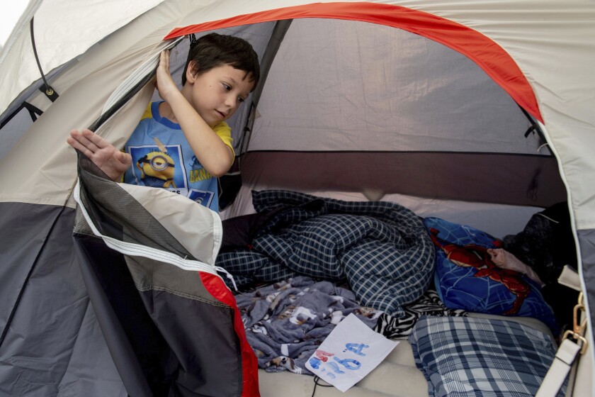 A child opens a tent flap at a church evacuation shelter.