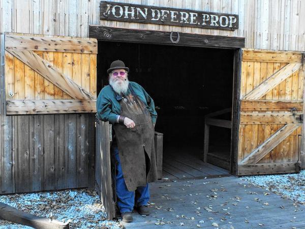 Rick Trahan poses outside a replica of the blacksmith shop in which John Deere created a plow that revolutionized farming.