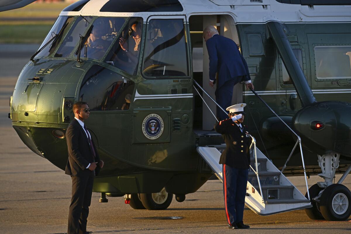 President Biden walks up the steps of the deep green Marine One helicopter.
