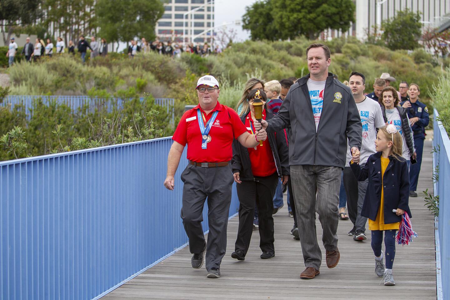 Newport Beach Mayor Pro Tem Will O'Neill carries a torch with Greg Kozlowski, Special Olympics Orange County Athlete of the Year, during a Unity Torch Walk around Newport's Civic Center Park on Thursday to raise funds for local Special Olympics participants.