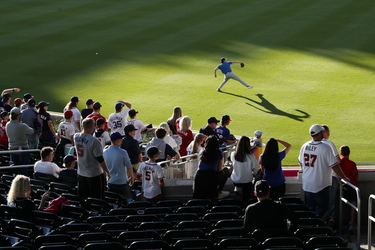 Fans watch Dodgers reliever Alex Vesia warm up in the outfield at Truist Park in Atlanta.
