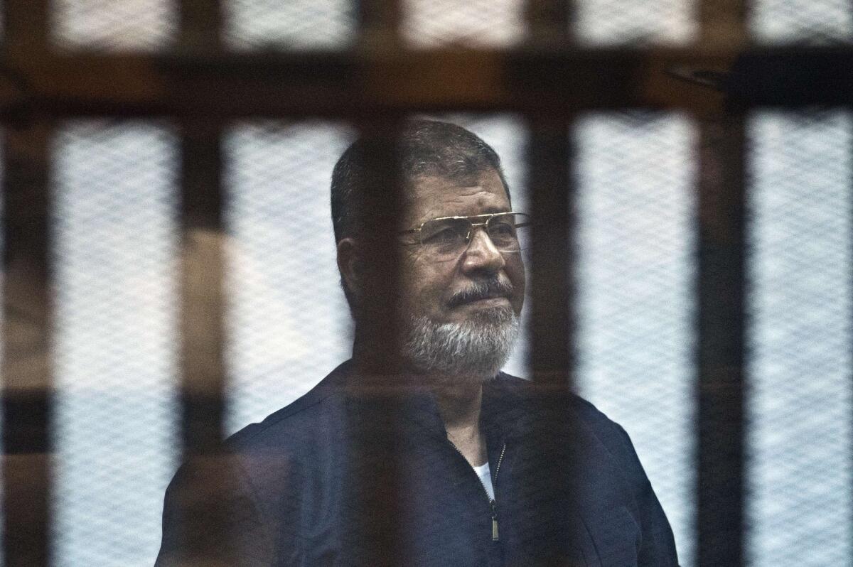 Egypt's ousted Islamist president, Mohamed Morsi, stands behind the bars during his trial in Cairo on June 16, 2015.
