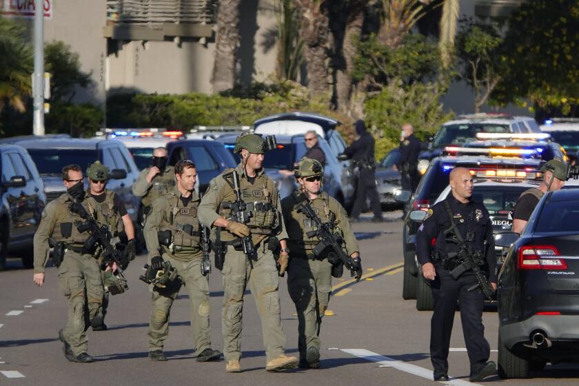 SAN DIEGO, CA - FEBRUARY 04: San Diego Police in tactical gear walk down Clairemont Mesa Blvd. after a shooting near Clairemont Drive after a shooting was reported on Thursday, Feb. 4, 2021 in San Diego, CA. One gun shot victim was transported and a male was taken into custody. (K.C. Alfred / The San Diego Union-Tribune)