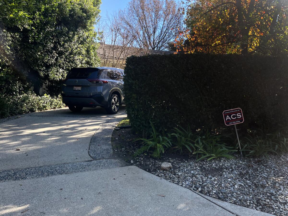 A sign for ACS Security next to a driveway.
