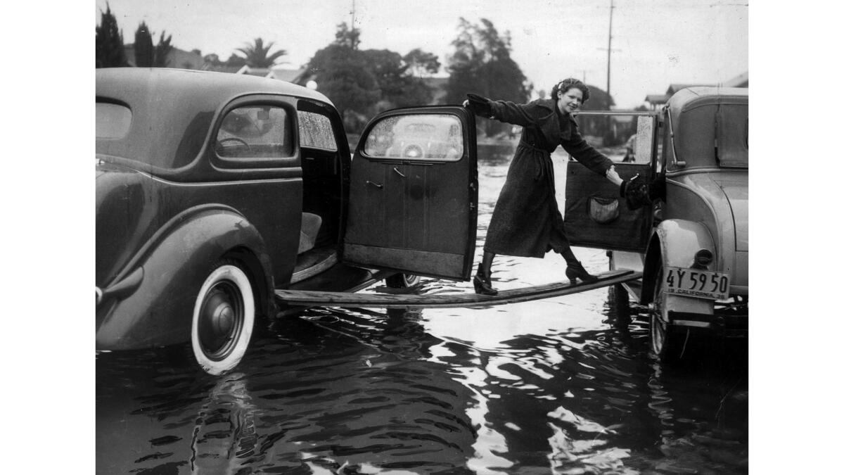 Feb. 11, 1936: After her car stalled out in curb-deep water, a friend of Helen Lawrence found a plank to serve as a bridge to another car.