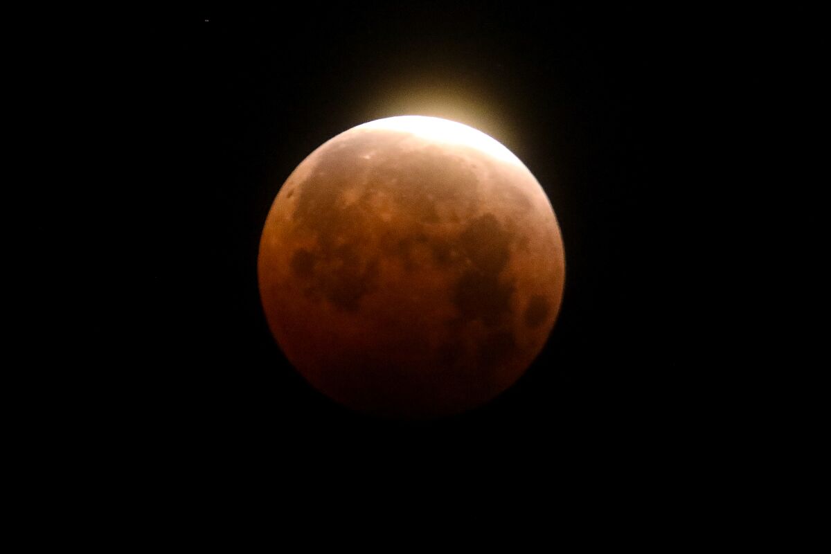 Light shines from a total lunar eclipse over Santa Monica Beach on May 26, 2021.