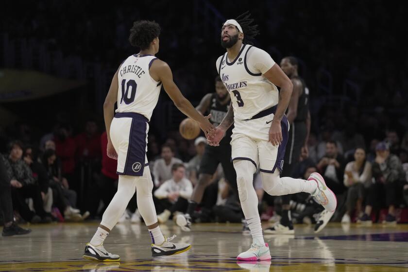Los Angeles Lakers guard Max Christie (10) and forward Anthony Davis (3) celebrate during a timout in the second half of an NBA basketball game against the Brooklyn Nets in Los Angeles, Sunday, Nov. 13, 2022. (AP Photo/Ashley Landis)