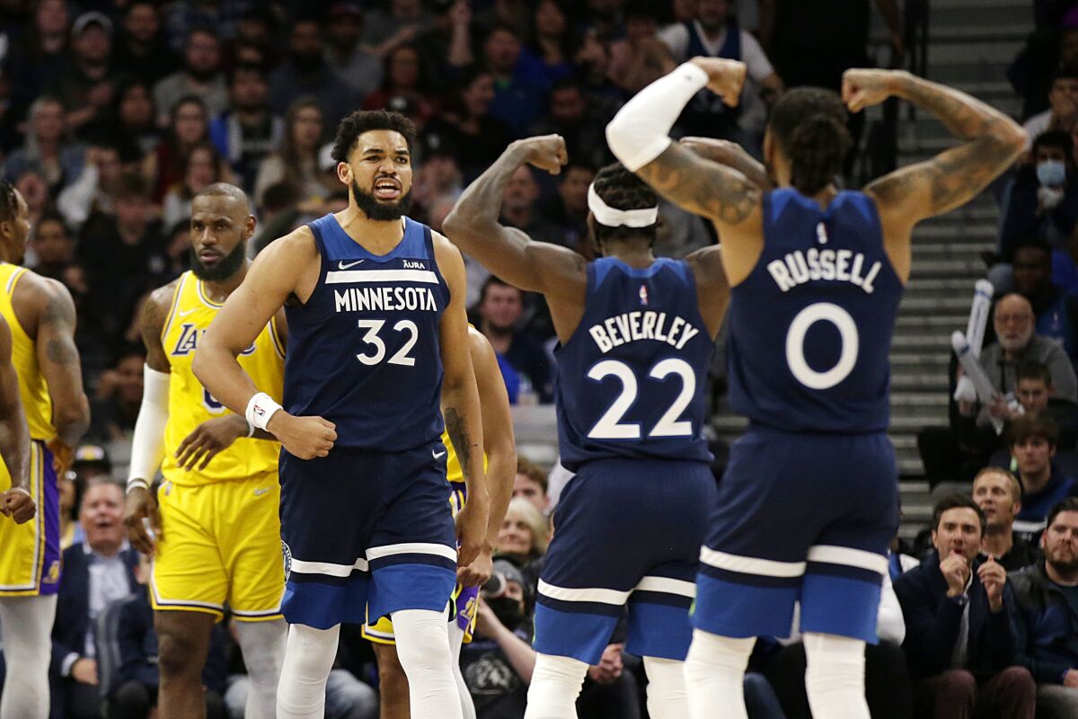 Minnesota Timberwolves center Karl-Anthony Towns (32) celebrates with Patrick Beverley (22) and D'Angelo Russell (0) during the second half of the team's NBA basketball game against the Los Angeles Lakers on Wednesday, March 16, 2022, in Minneapolis. (AP Photo/Andy Clayton-King)