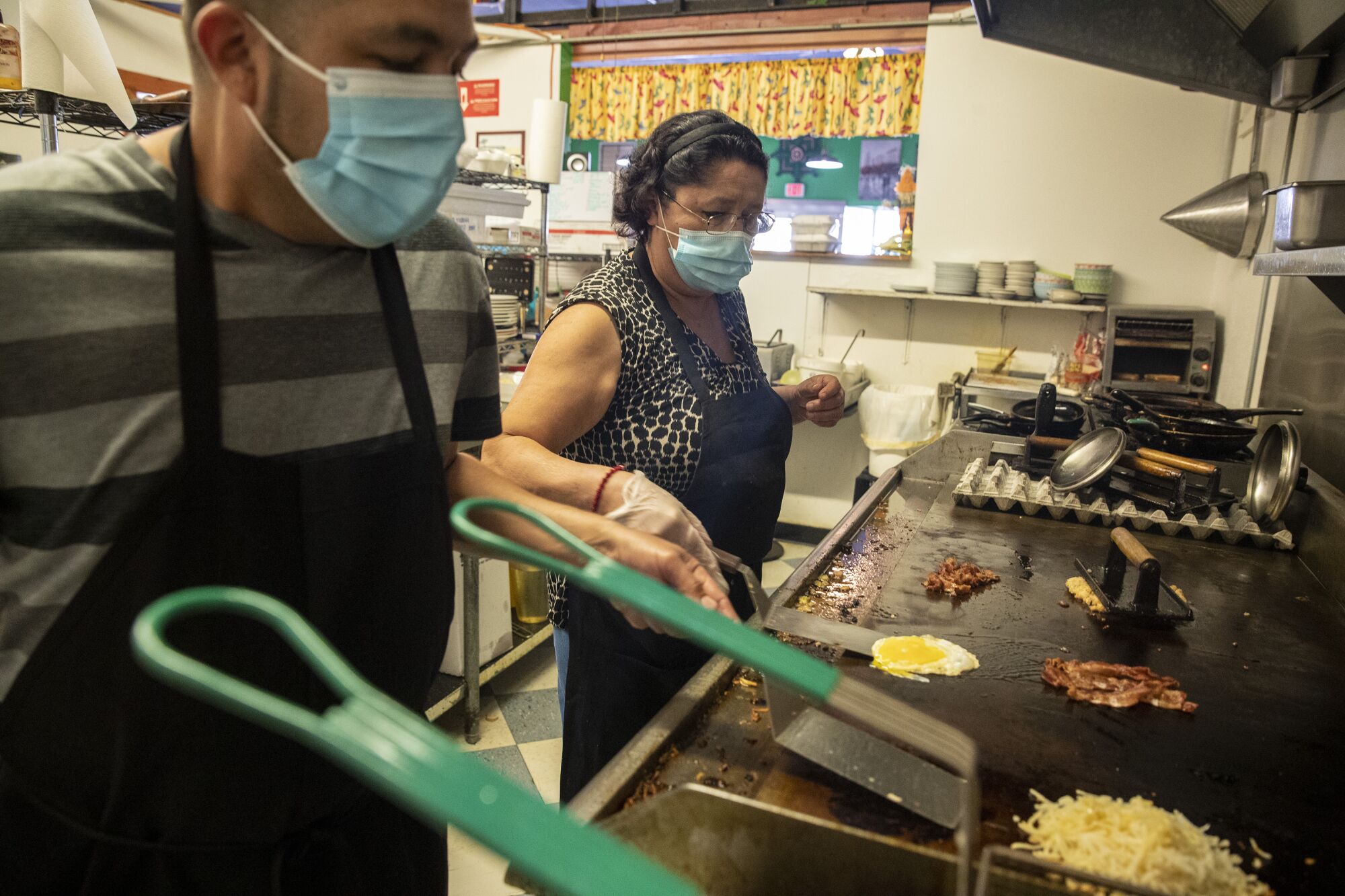 Line cook Jesus Rodriguez, left, prepares meals with Francisca, right, a chef at a local cafe in Bisbee.