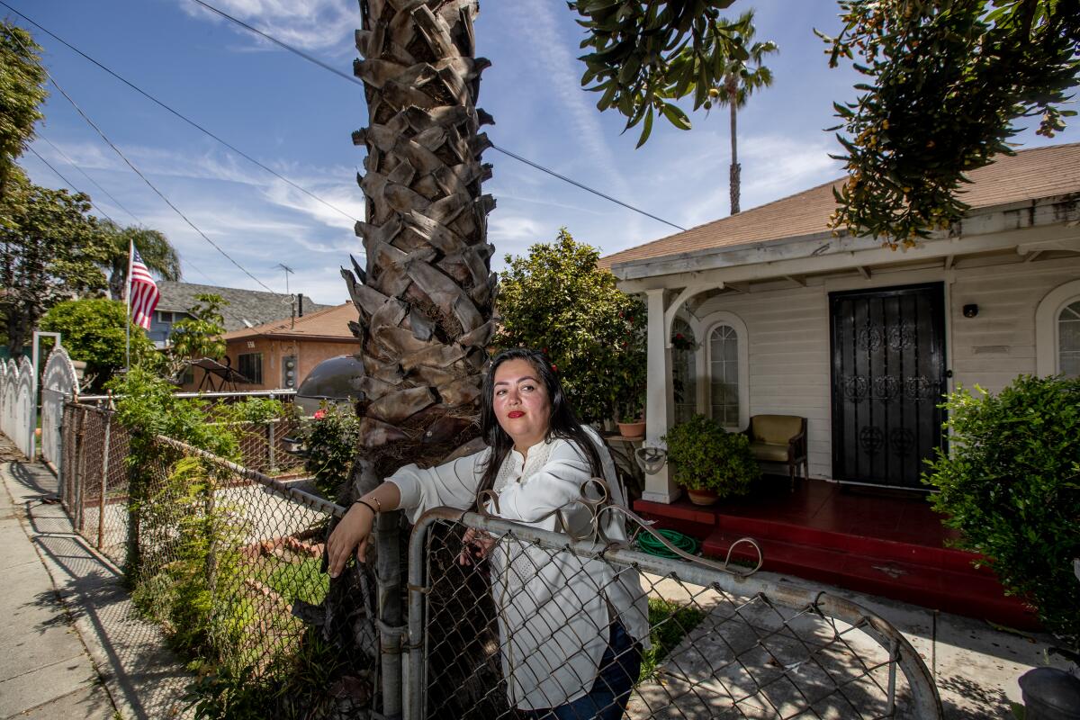 Wendy Carrillo stands by house next to palm tree trunk