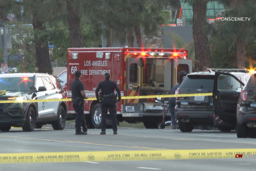 Police cruisers next to a Los Angeles Fire Department ambulance behind yellow police tape