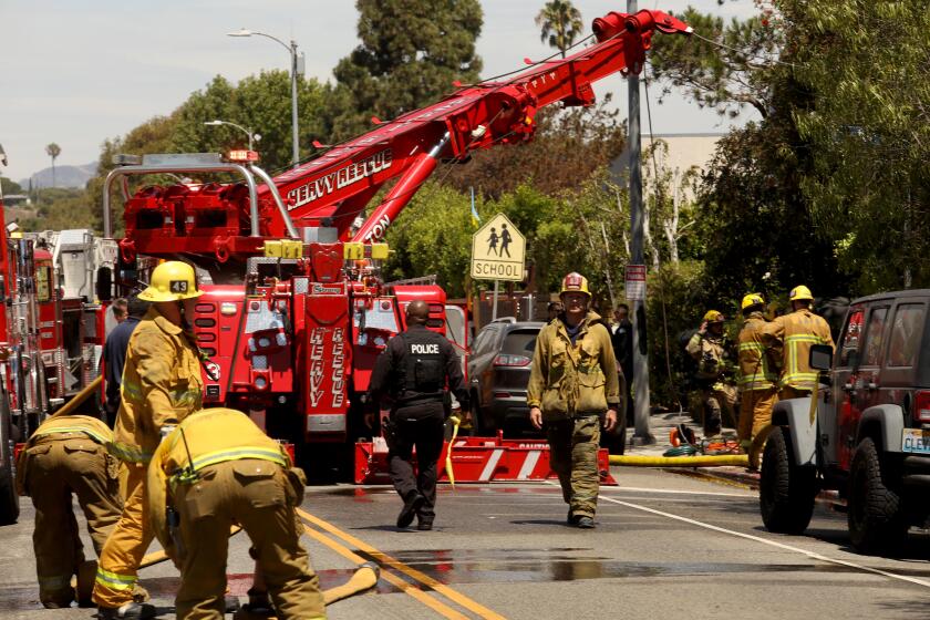 MAR VISTA, CA - AUGUST 5, 2022 - - Firefighters work the site where a vehicle crashed into a house in the Mar Vista critically injuring the motorist and sparking a fire on August 5, 2022. The crash was reported shortly before 11 a.m. in the 1700 block of South Walgrove Avenue, said Brian Humphrey of the Los Angeles Fire Department. ``The solo passenger vehicle struck and came to rest well within a 738- square-foot two-story home, built in 1952, causing structural compromise and erupting in heavy fire prior to LAFD arrival,'' Humphrey said in a statement. (Genaro Molina / Los Angeles Times)