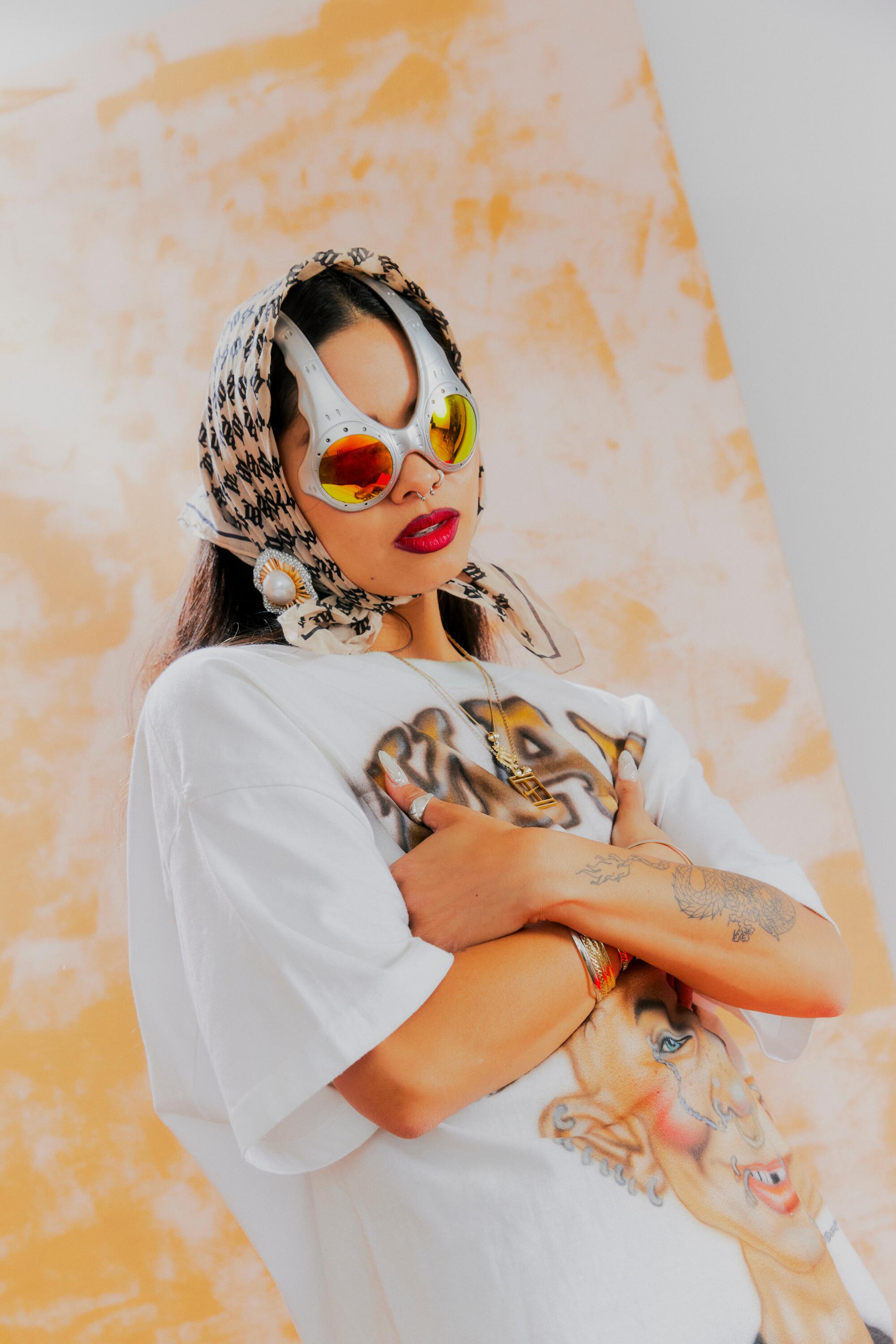 Ann-Marie Hoang posing in a headscarf, Over the Top sunglasses and a graphic T-shirt.