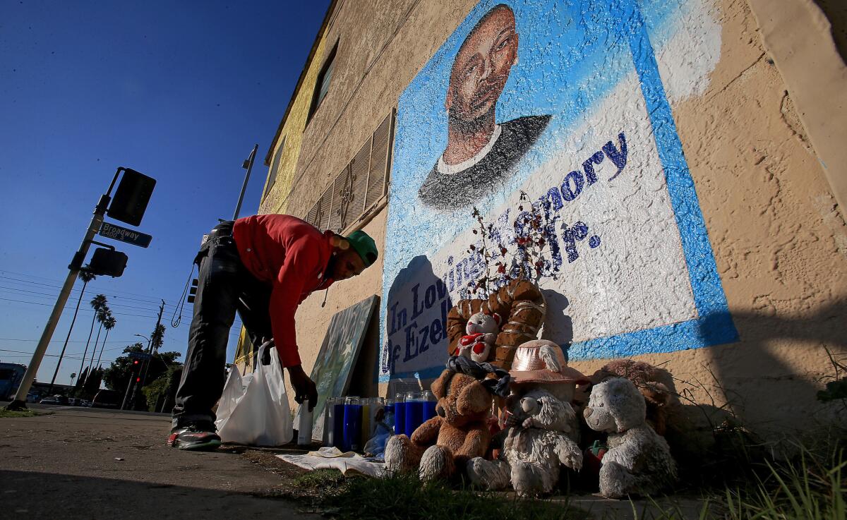 Lavell Ford, the brother of Ezell Ford, puts votive candles at the foot of a memorial to Ezell, who was shot and killed by LAPD officers in August.