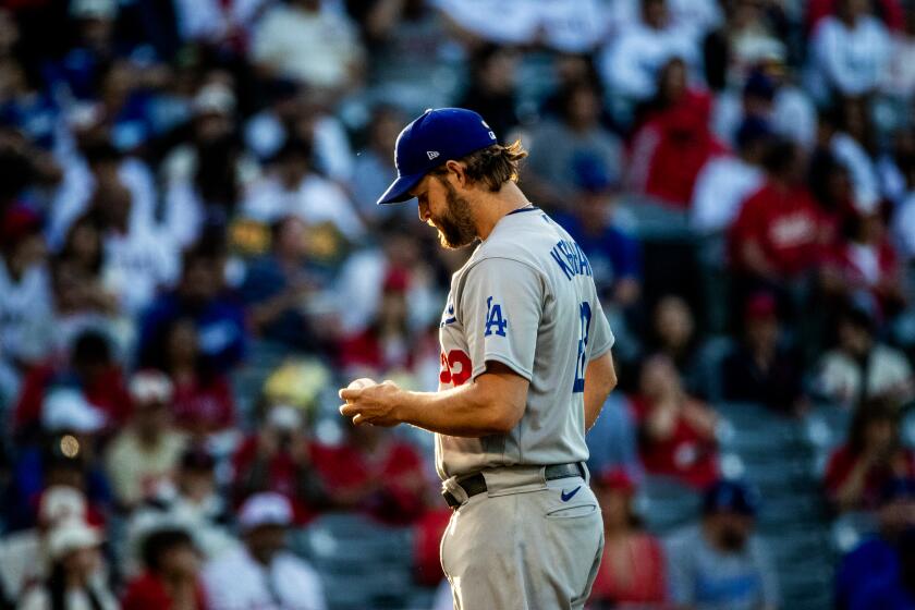 Dodgers starting pitcher Clayton Kershaw stares down at the ball before throwing his first pitch 