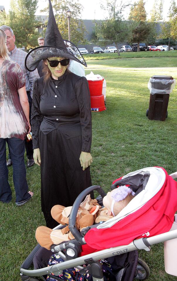 Susan Wolfson, account clerk for the city of La Cañada Flintridge, dressed as the Wicked Witch and Morgan Alameda, 9 months, of Pasadena who is dressed as the Cowardly Lion, spend a moment looking at one another at Olberz Park in La Cañada Flintridge at the annual La Cañada Flintridge Chamber of Commerce mixer on Thursday, September 17, 2015.