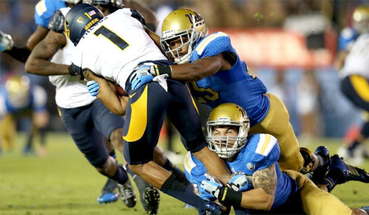 UCLA's Ryan Hofmeister, bottom, grabs at California's Bryce Treggs' feet to pull down the wide receiver during the Bruins' 37-10 win on Oct. 12.