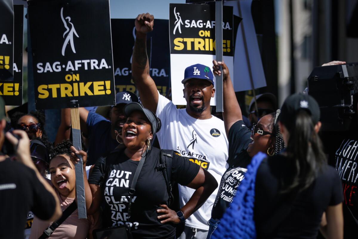 People march with "SAG-AFTRA on Strike" signs.